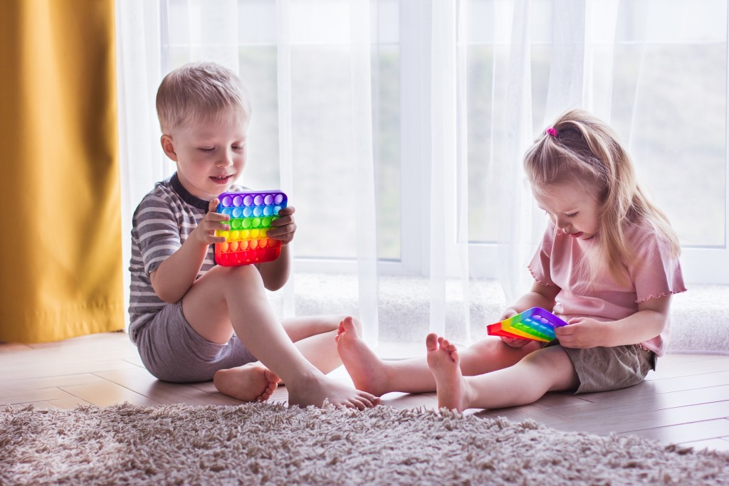 Blonde boy and girl Kids play with pop it sensory toy